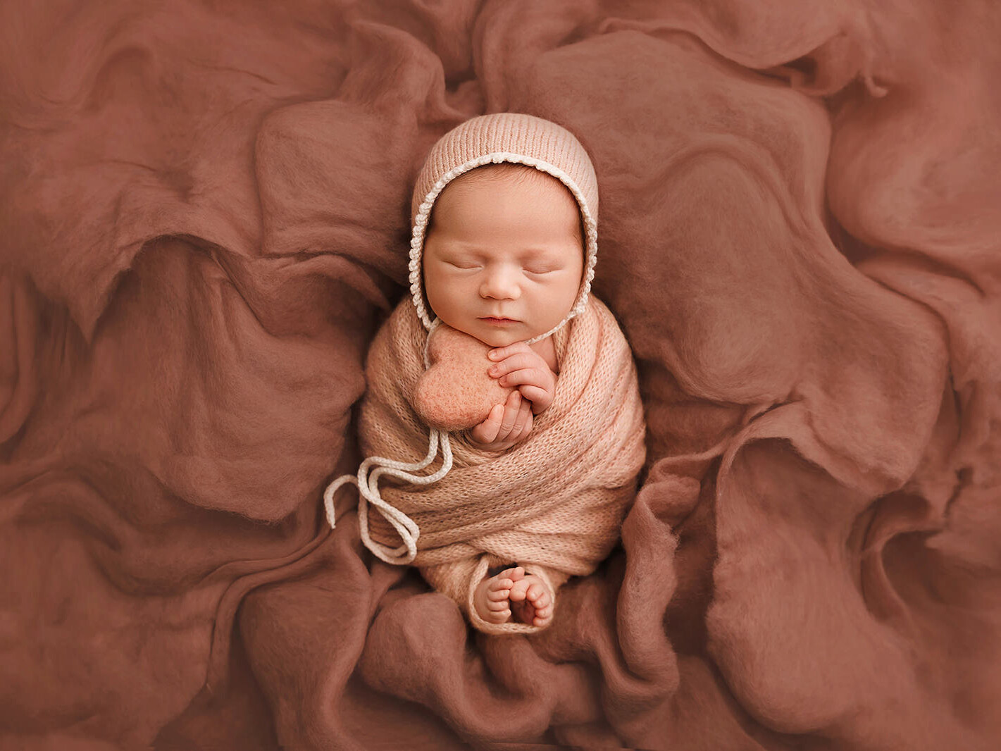 newborn baby girl photoshoot, in pink wrap, pink hat and pink heart, picking toes
